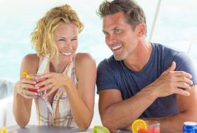 Happy couple drinking cocktails on a luxury crewed yacht